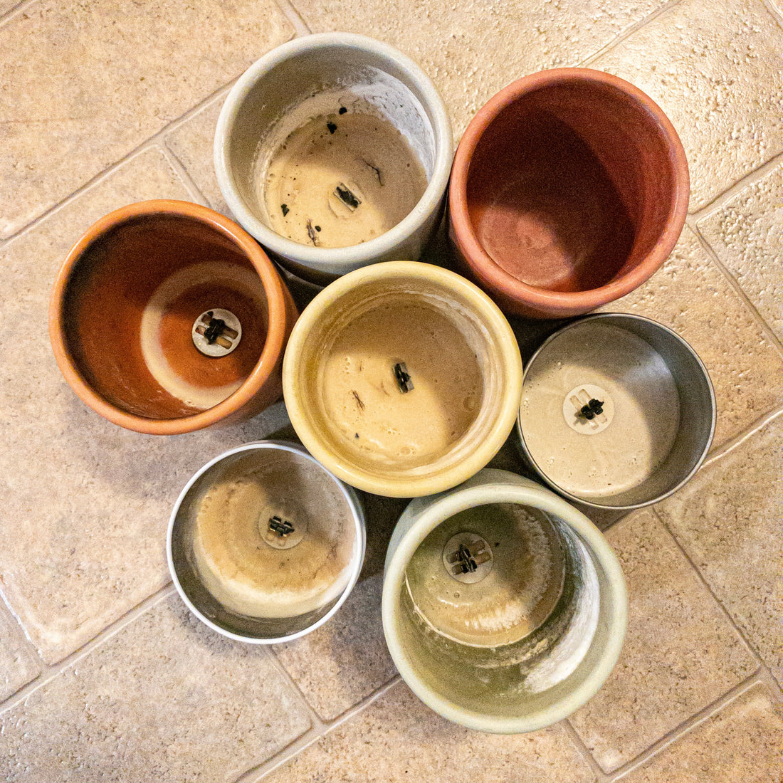 Several used candle tins and concrete jars, ready to be cleaned and recycled into new candles.